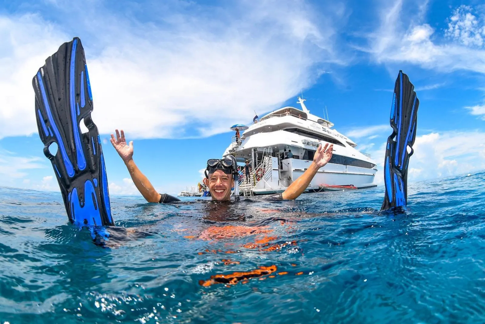 Snorkeller waving fins in the air beside the cruise boat