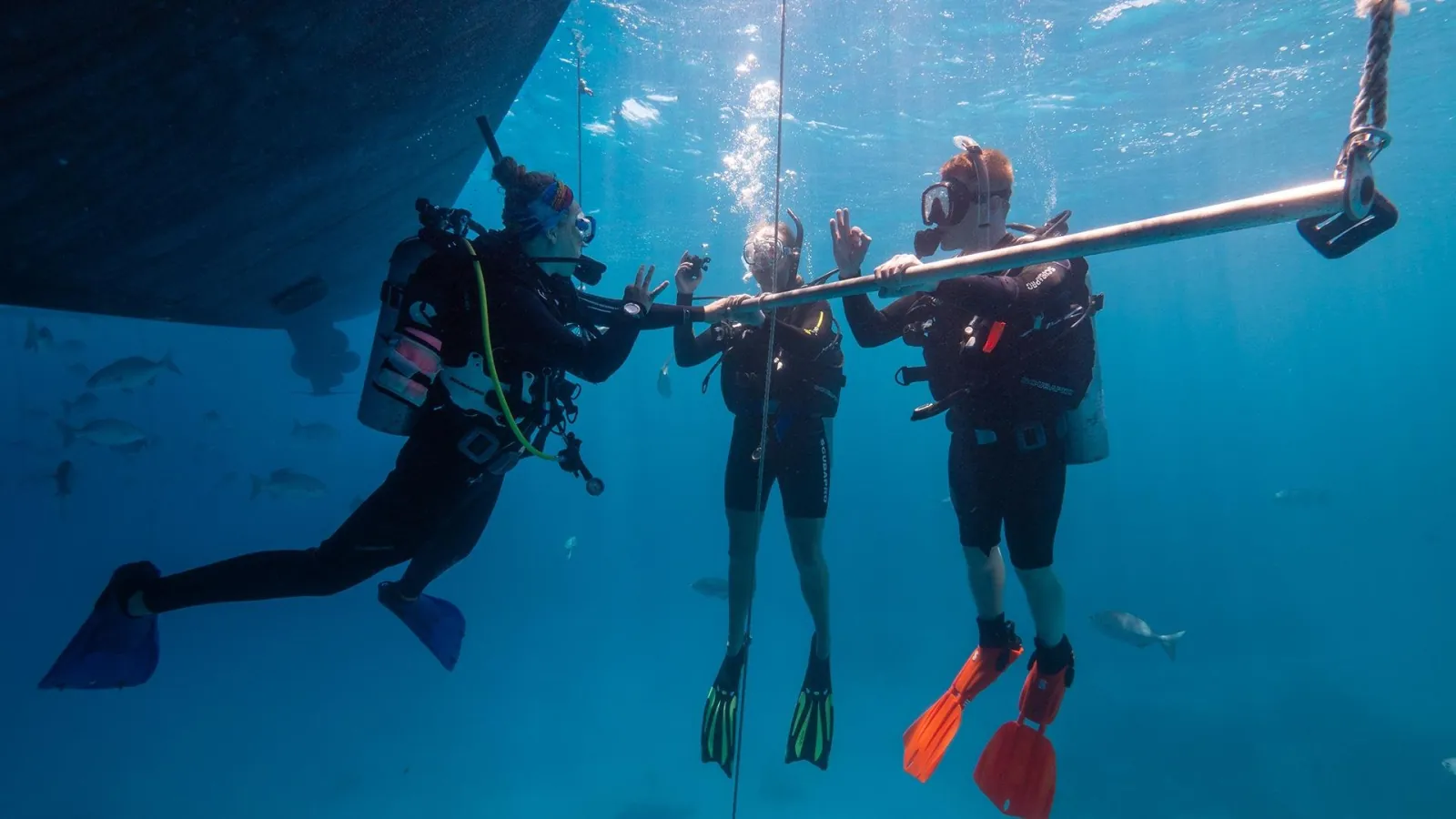 Group of divers hovering beside the boat hull