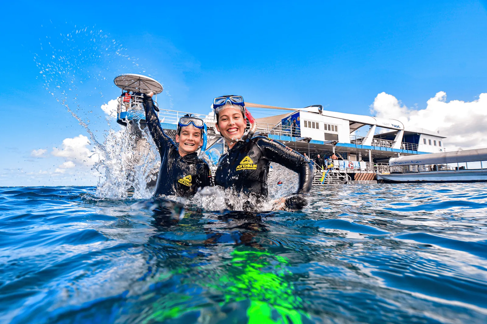 Two snorkellers waving at the pontoon