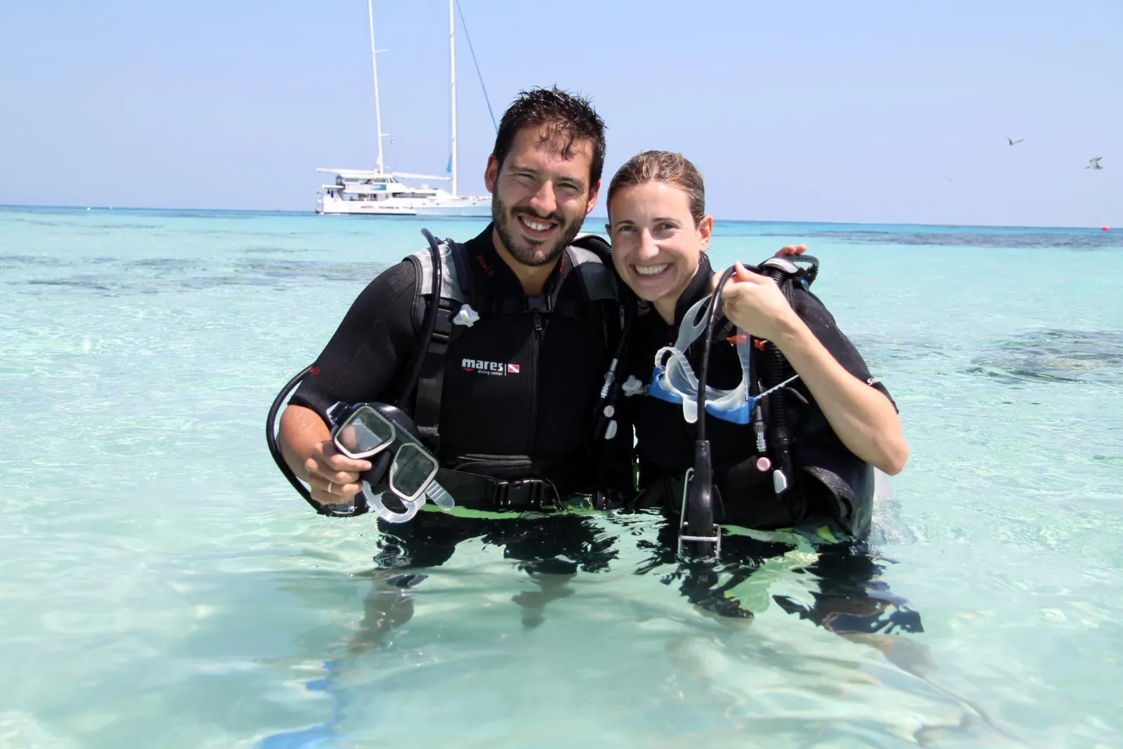 Two divers standing in the shallows in dive gear