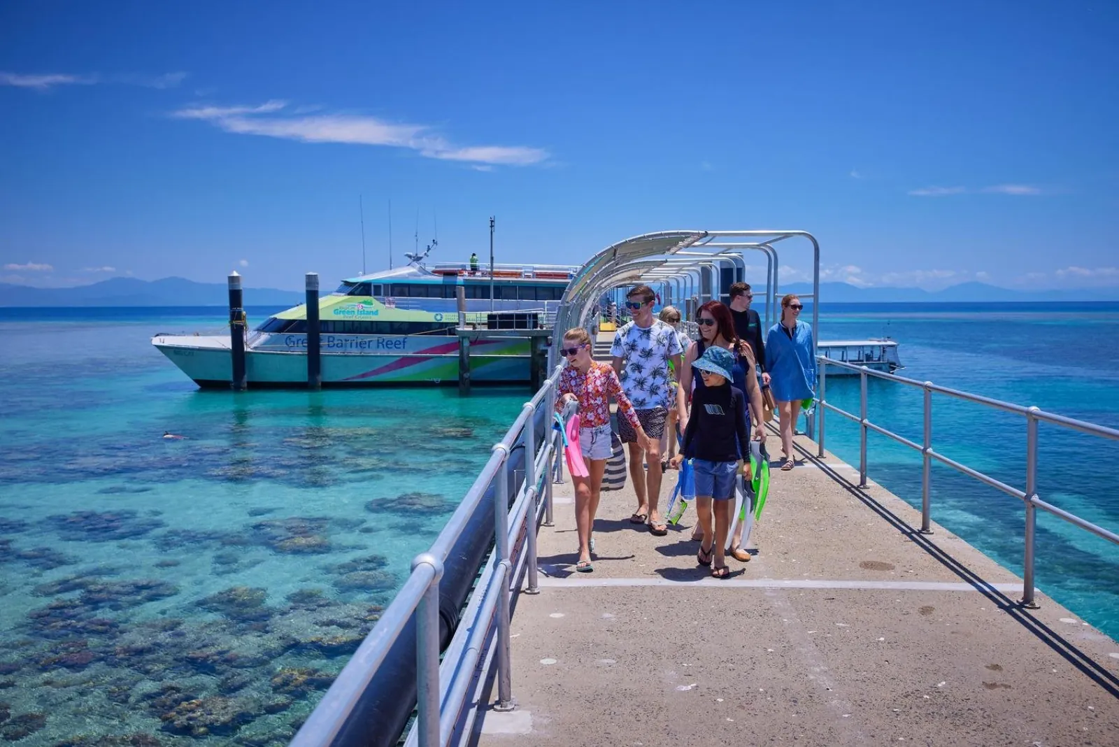 Passengers walking along the Green Island jetty from the catamaran