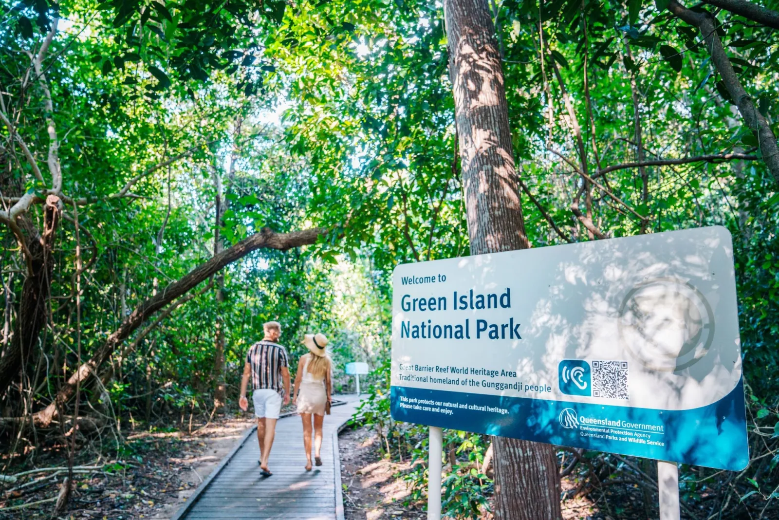 Visitors on the rainforest boardwalk by the national park sign