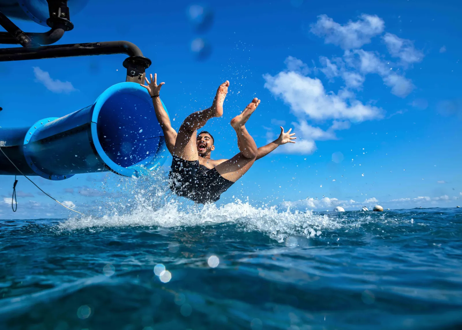 Guest splashing down a water slide into the sea