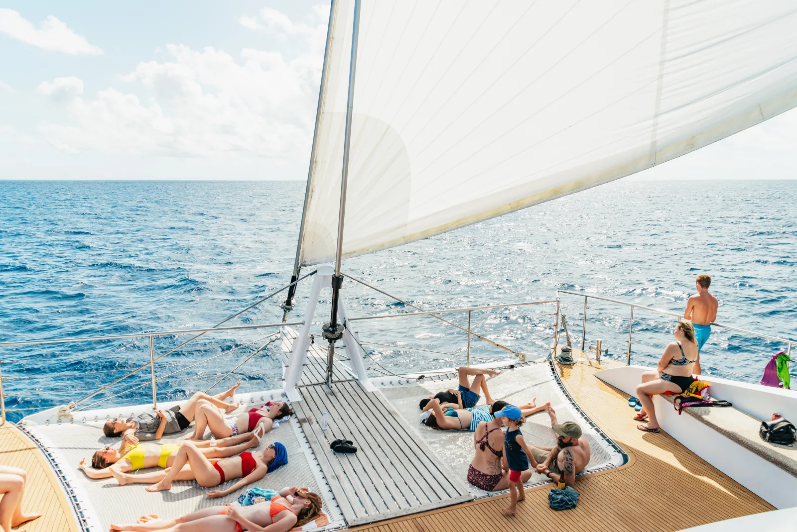 Guests relaxing on the sunny trampoline deck of a sailing catamaran